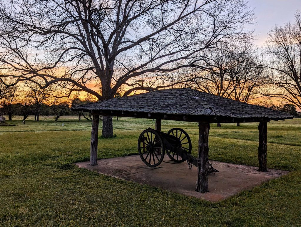 Photo of cannon under a shelter at sunset