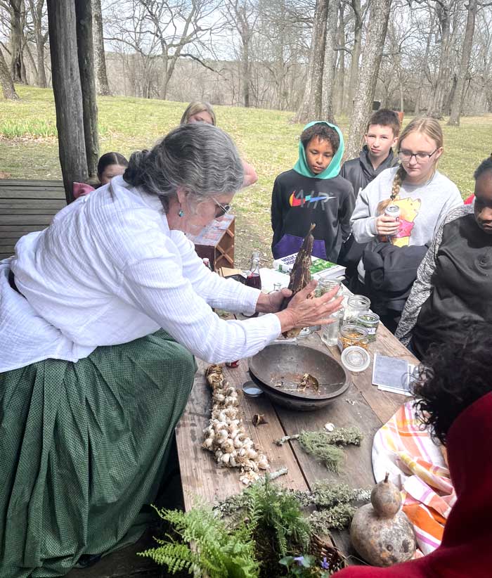 Students watch an instructor work with herbs, roots, and plants.