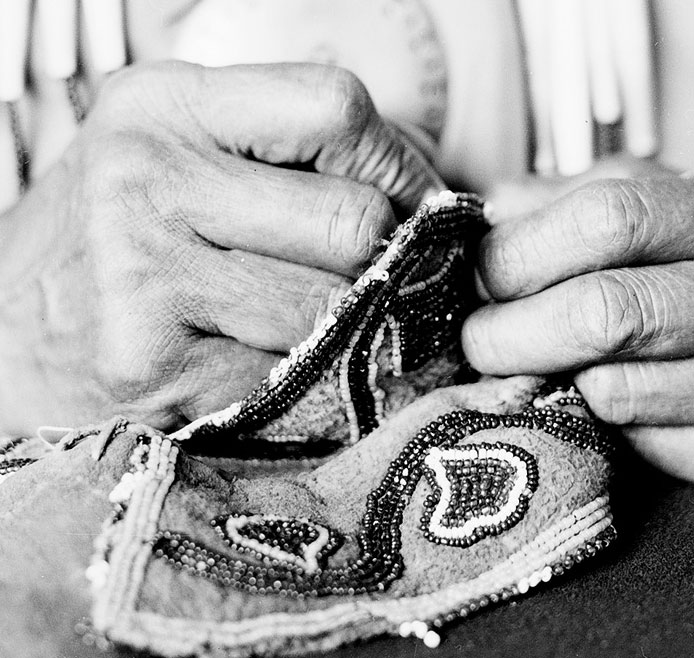 Close-up of hands performing intricate beadwork